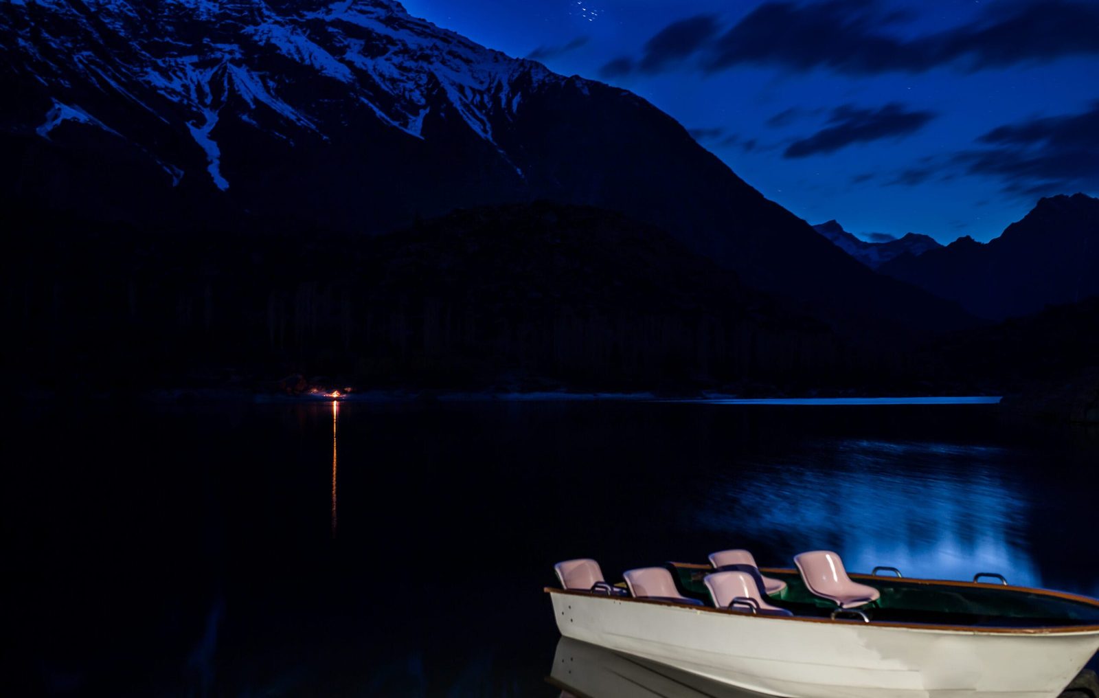 Upper Kachura Lake at dusk with a wooden rowing boat and mountains behind