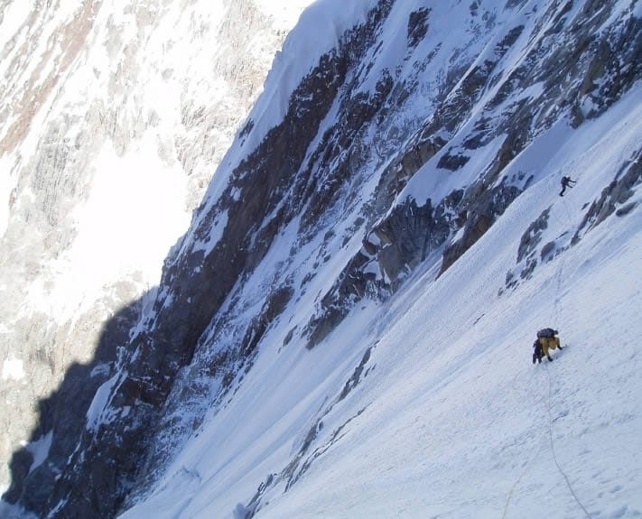 Alpinista che traversa una cengia nevosa sulla parete sud-ovest del Khunyang Chhish East