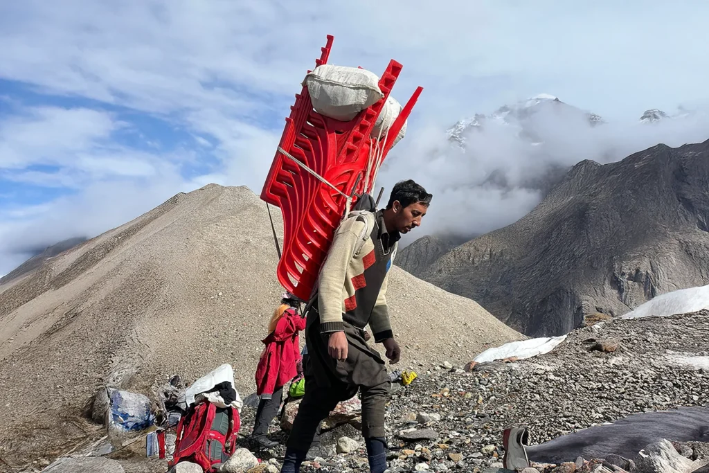 Porteur avec un cadre de portage en bois au camp de base d'une expédition